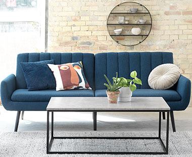 Sininen vuodesohva ja harmaa betonijäljitelty sohvapöytä