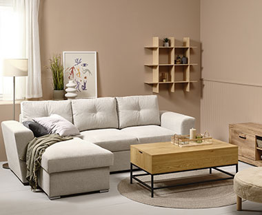 Vaaleanharmaa divaanivuodesohva, sohvapöytä ja seinähyllykkö olohuoneessa