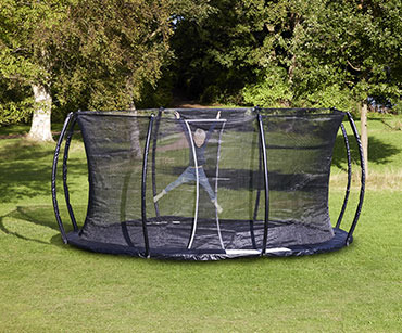 Musta trampoliini kesäisellä nurmella