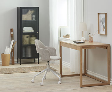 Harmaa tyylikäs työtuoli ja puinen työpöytä ja musta lasivitriini