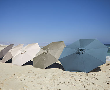 Erivärisiä aurinkovarjoja rannalla