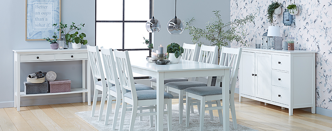 Ruokailutilan valkoiset kalusteet: sivupöytä, ruokapöytä, ruokapöydän tuolit ja senkki