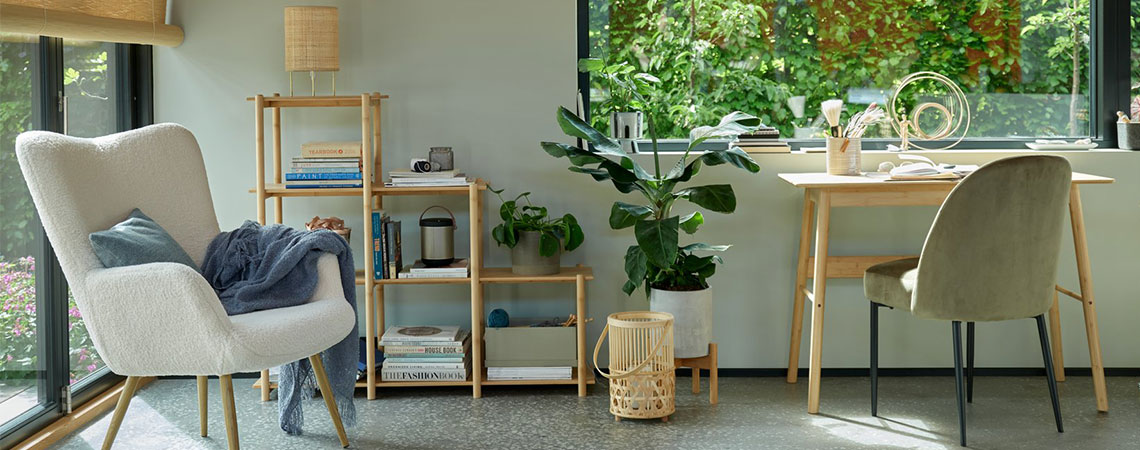 Harmaa nojatuoli ikkunan vieressä ja bambuinen huoneenjakaja taustalla. Bambulyhty lattialla bambupöydän ja oliivinvihreän ruokapöydän vieressä