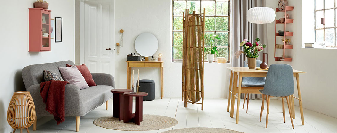 Olo/ruokailuhuone, jossa ruusunvärinen seinäkaappi, harmaa vuodesohva, bambu -pukeutumisermi, bambupöydät ja harmaat ruokapöydän tuolit