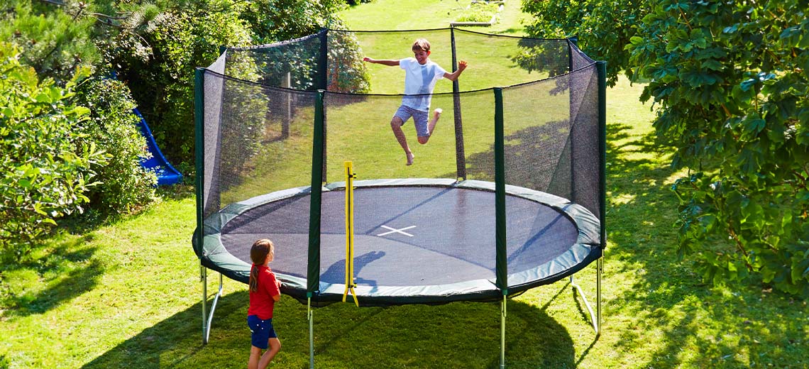Lapset leikkimässä suurella trampoliinilla pihalla 