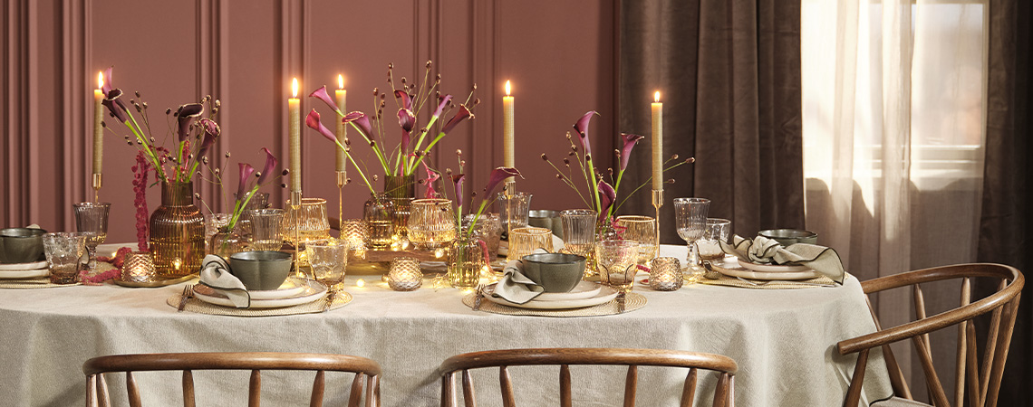 Juhlavasti katettu joulupöytä, joka toivottaa joulun pyhät tervetulleiksi Juhlavan jouluinen kattaus syvissä väreissä, kuten viininpunainen, vihreä ja harmaa