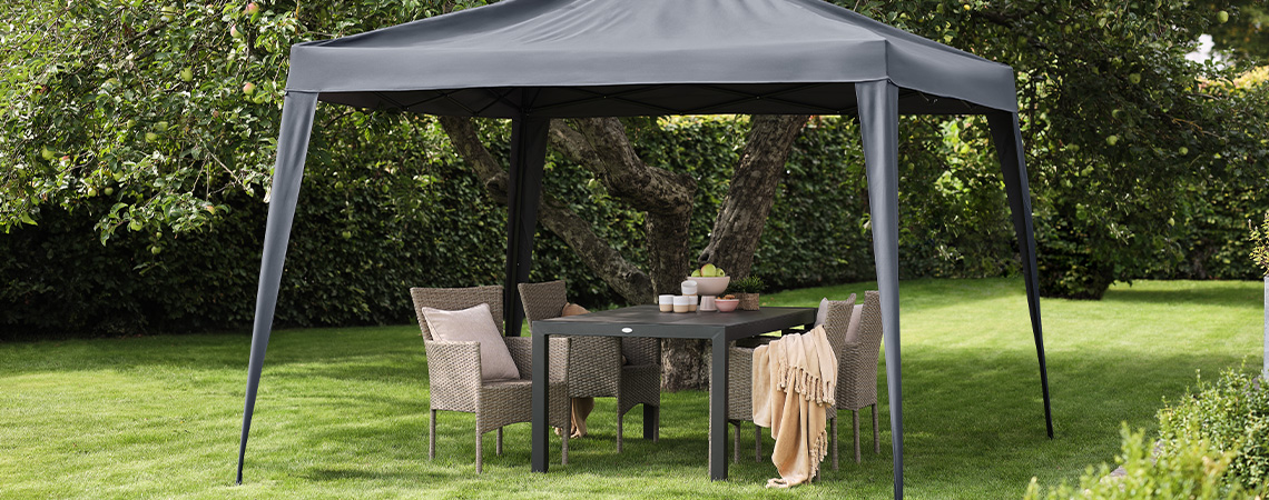 Harmaa paviljonki pihalla puutarhakalusteiden kanssa