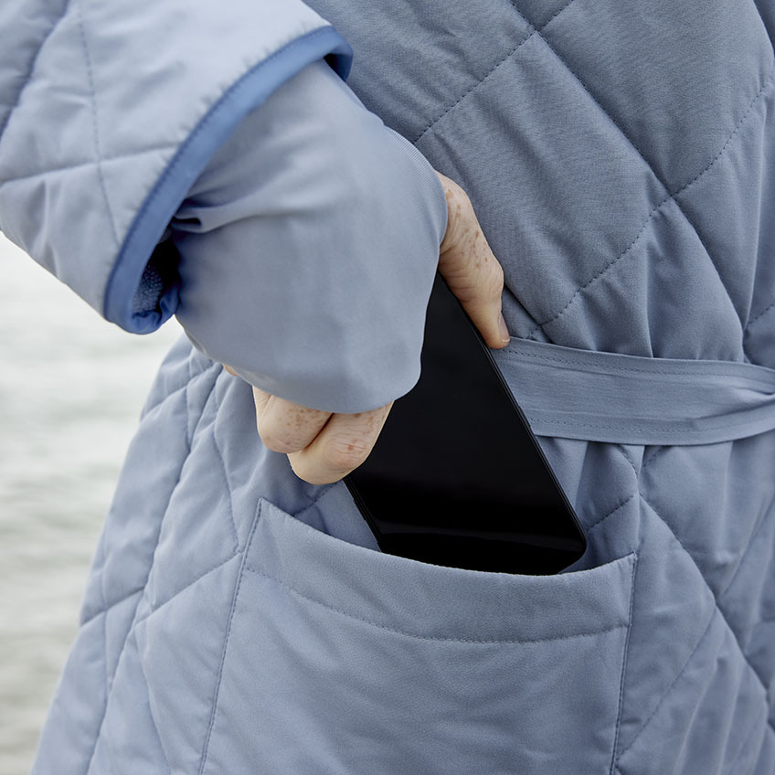 Person putting a mobile phone in a bathrobe pocket 