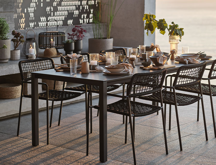 Puutarhapöytä ja puutarhatuolit, pöytä katettu terassille illallista auringonlaskussa varten