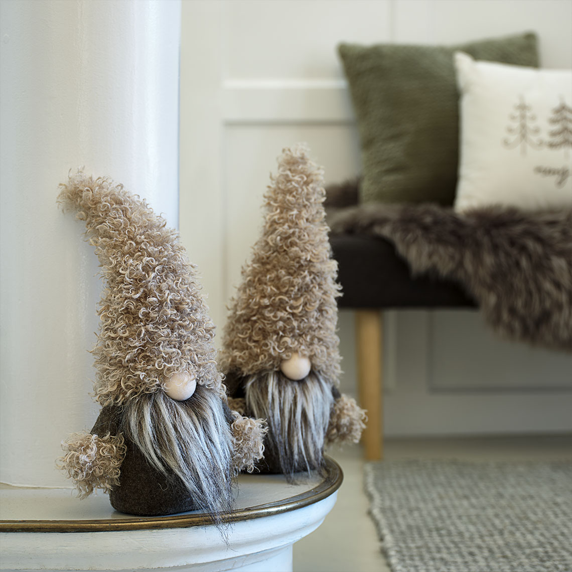 Pieniä, koristeellisia joulutonttuja vihreän ja ruskean sävyissä senkin päällä