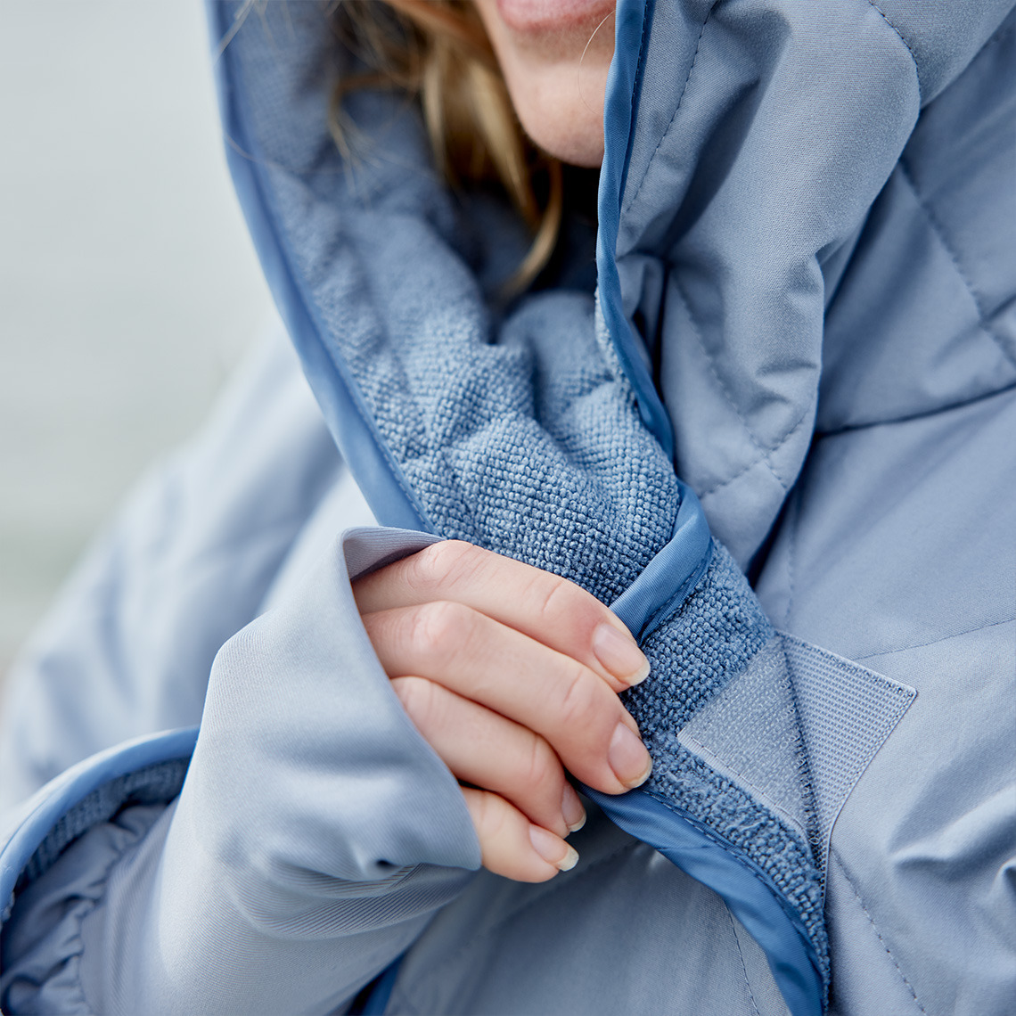 OSBY:ssa on tarranauhakiinnitys, mikä auttaa pitämään sinut lämpimänä Talviuintiin suunniteltu talvikylpytakki, jossa on tarranauhalla toimiva kiinnitys, mikä auttaa pitämään sinut lämpimänä