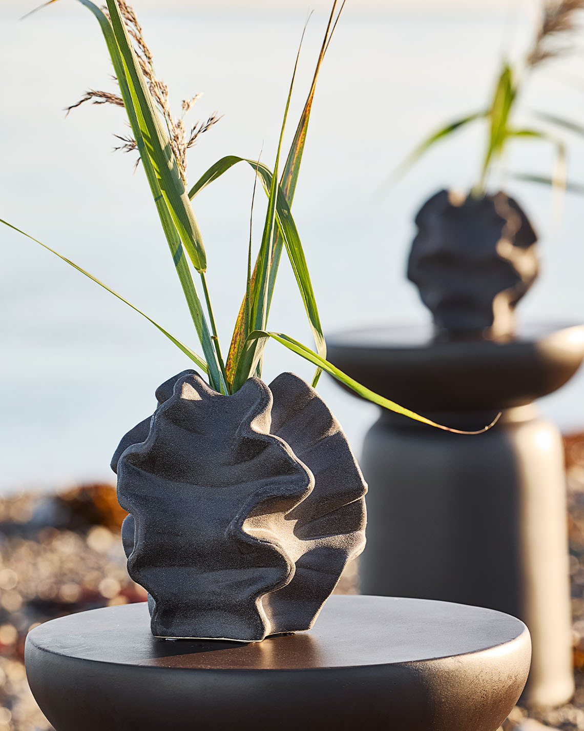 Orgaanisen muotoinen maljakko rannalle sijoitetulla jalustalla