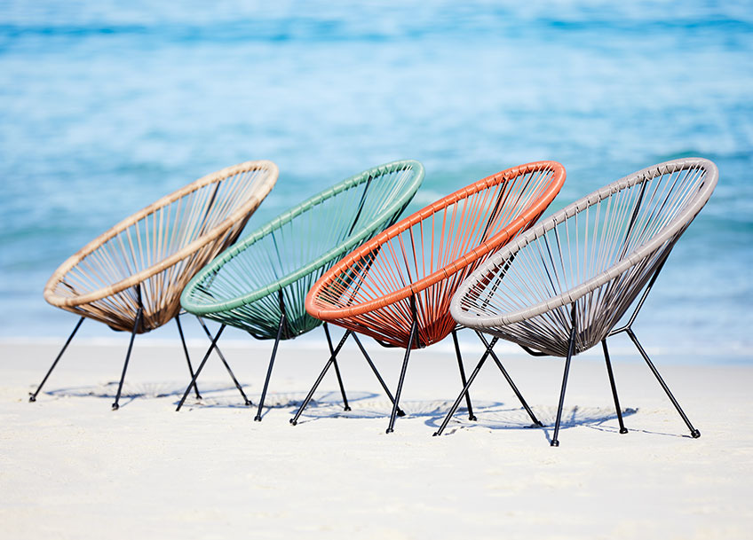 UBBERUP lounge chairs available in green, grey, red and sand Four garden lounge chairs in different colours on a beach