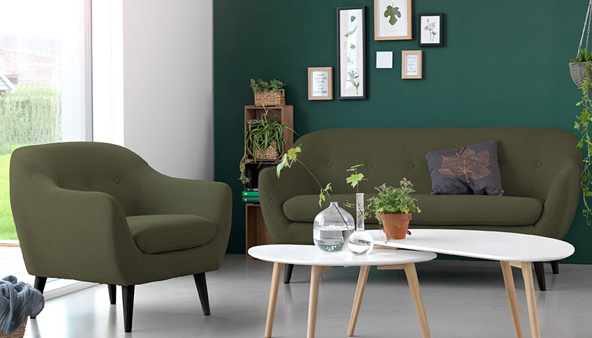  Olohuoneessa vihreä samettinen sohva ja nojatuoli ja kaksi sohvapöytää