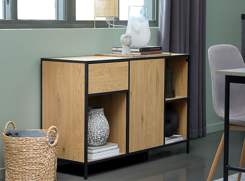 TRAPPEDAL sideboard in oak and black with the MATHIAS vase An oak sideboard beneath a window in a dining room