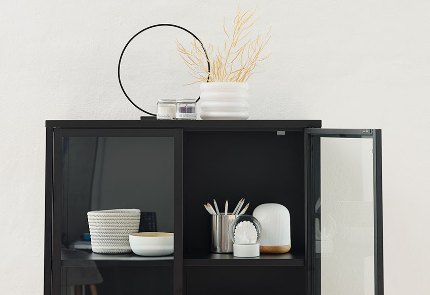 Tea light holder and flowerpot on top of a black display cabinet