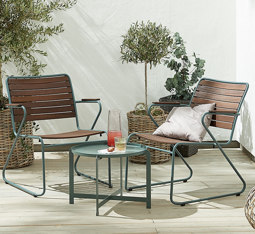 GASSUM lounge chairs and BORRE lounge table Two wooden garden lounge chairs with green frame and a small green side table on a patio