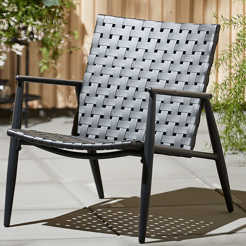 EDDERUP lounge chair is also available in nature colour Black garden lounge chair on a patio