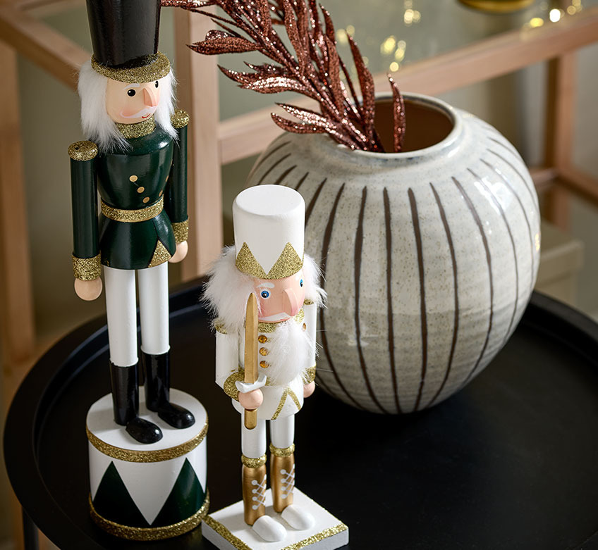 VALI and EUKLAS nutcracker figurines and SOFUS vase on RANDERUP end table Two Christmas figurines and a vase on a black end table