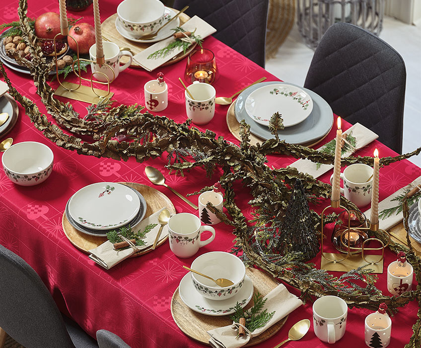 Christmas dinner setting with red tablecloth and gold cutlery 
