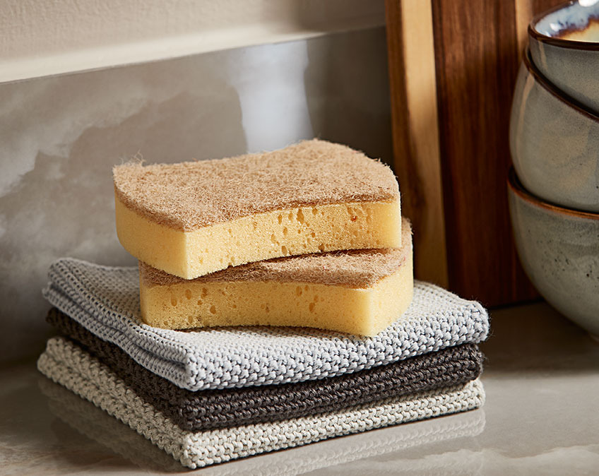 Dishcloths and cleaning sponges in a stack on a kitchen table 