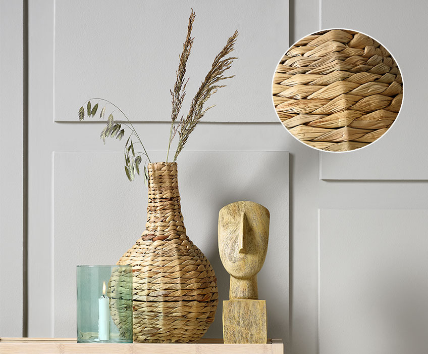 Wicker vase, wooden sculpture of head and candle holder placed on a console table
