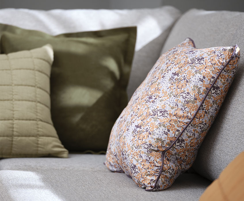KAMILLE floral cushion, ALM green suede cushion and VALUME quilted cushion Grey sofa with floral and green cushions