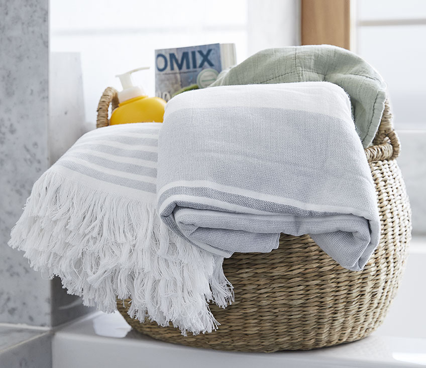 Basket with beach towels, quilted blanket, a magazine and sunscreen  