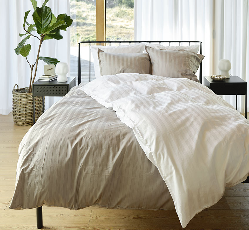 NELL-pussilakanasetit Bedroom with grey and white striped bedding on the bed and two bedside tables