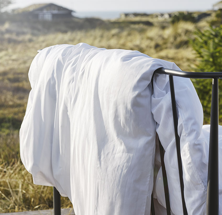 NELL-pussilakanasetti valkoinen Duvet hanging over a fence in a natural setting