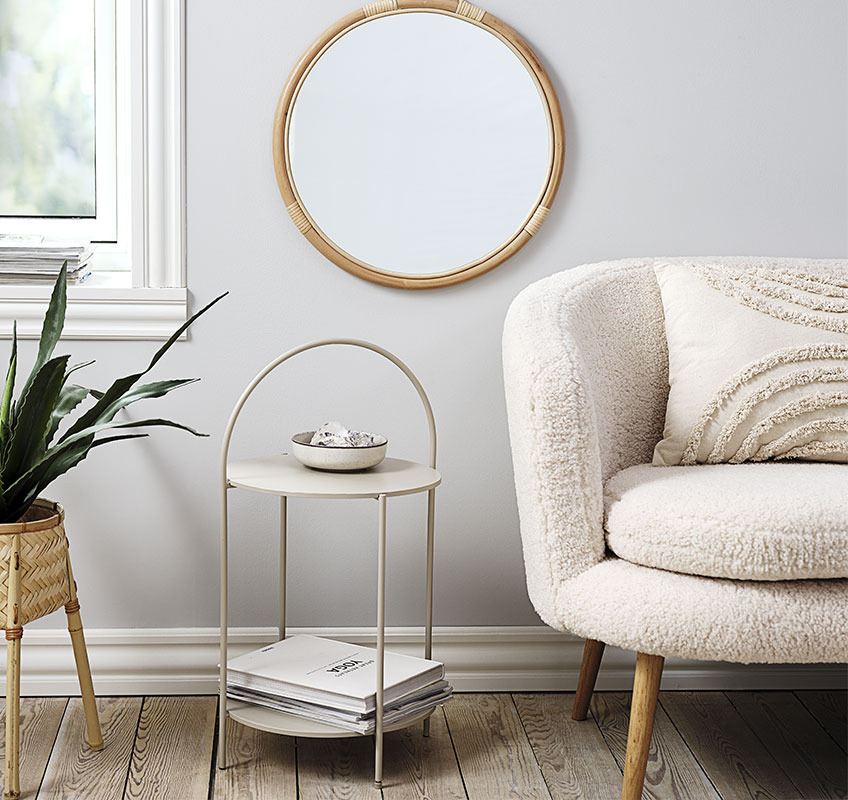 Round end table in light beige and round mirror in rattan