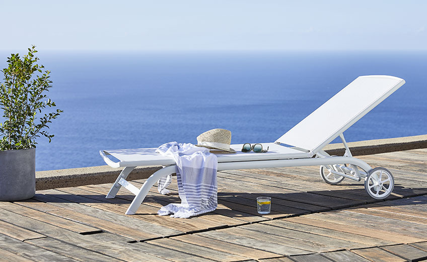 White sun lounger with wheels by the ocean