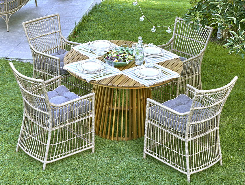 Round garden table with a centred base and four garden chairs on a lawn 