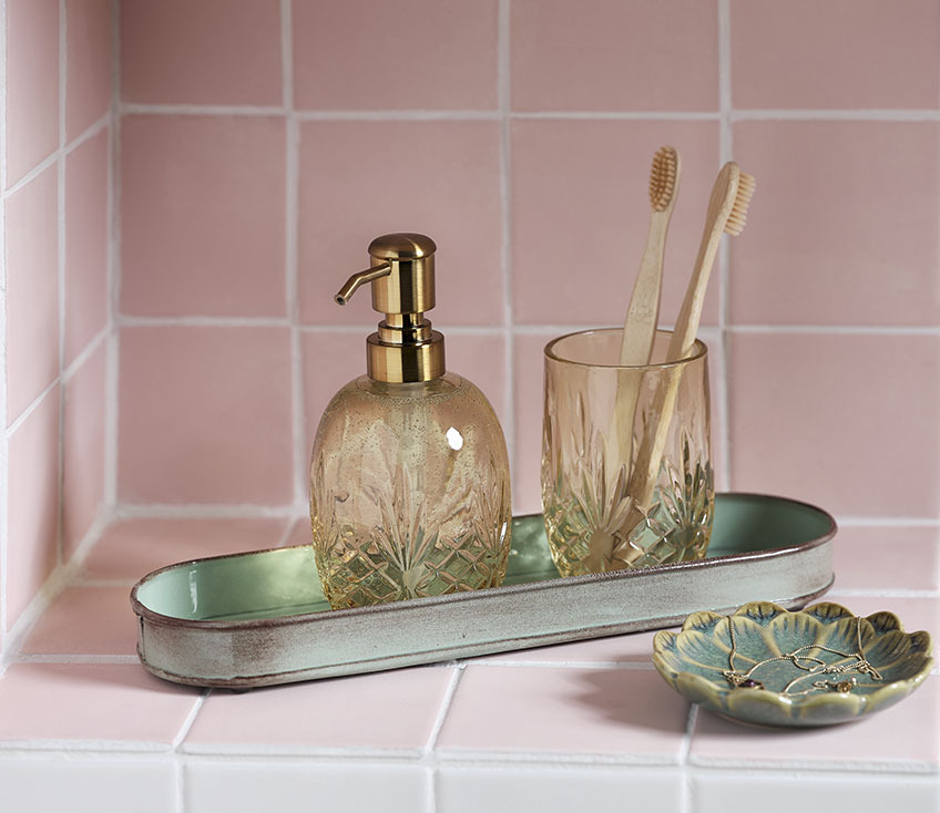 Soap dispenser, toothbrush holder with toothbrushes and jewellery tray in a bathroom 