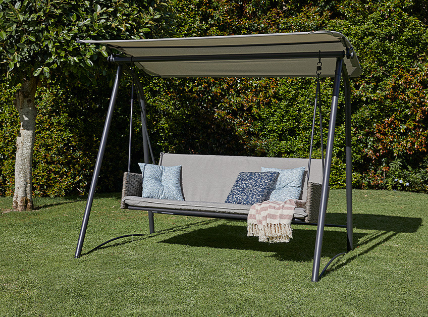Grey hanging sofa in garden with cushions and throw